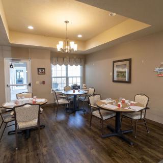 An elegantly set dining area with multiple tables and chairs, illuminated by a chandelier.