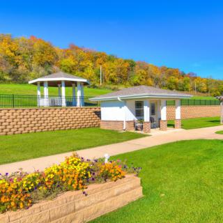 Beautiful park landscape with gazebos, greenery, and a pathway on a sunny autumn day.