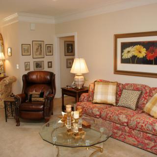 A cozy living room with a patterned sofa, armchair, coffee table, and decorative artwork.