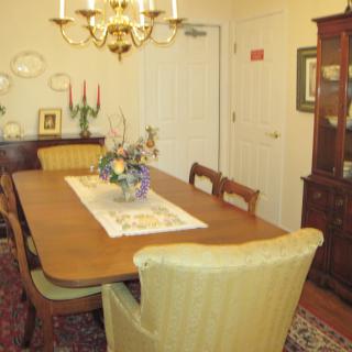 A vintage-style dining room with a wooden table, upholstered chairs, and a chandelier.