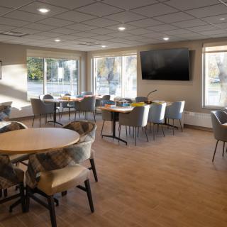 A modern dining area with tables, chairs, and a wall-mounted television.