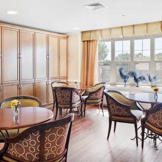A bright dining area with several tables and chairs, illuminated by natural light from the large window.