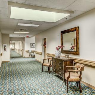 A quiet hallway with decorative furniture and a large mirror.