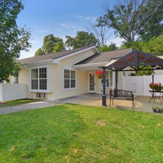 A cozy backyard with a small patio and outdoor seating, surrounded by a well-maintained lawn and trees.