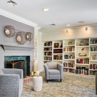 A cozy living room with bookshelves filled with books, a fireplace, and comfortable seating.