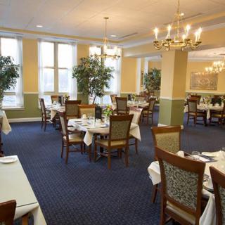 An elegant dining room with neatly arranged tables and chairs, featuring chandeliers and decor.