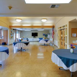 A spacious community hall set up for an event, featuring neatly arranged tables and a bright, inviting atmosphere.