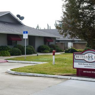 A one-story office building with a sign in front surrounded by a landscaped area and parking lot.