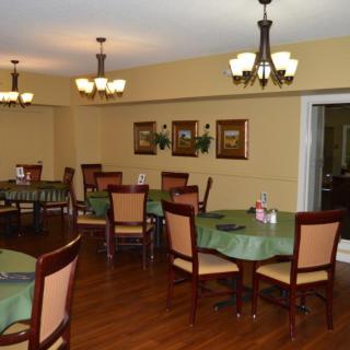 A cozy dining room with neatly arranged tables and chairs, featuring warm lighting and elegant decor.