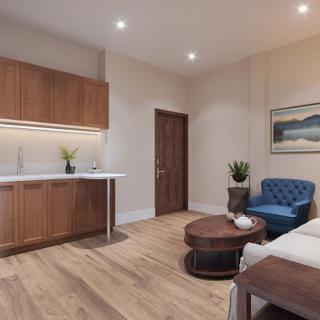 A modern living space with a kitchenette, featuring wood flooring, comfortable furniture, and soft lighting.