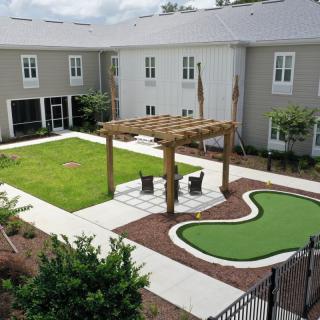 A well-maintained courtyard with a pergola and seating area surrounded by a manicured lawn and landscaping.