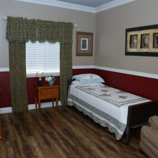 A cozy bedroom with a single bed, wooden flooring, and decorative wall art.
