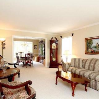 A traditional living room with a sofa, armchair, grandfather clock, and coffee table.
