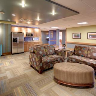 A cozy and modern lounge area featuring comfortable seating and a kitchenette.