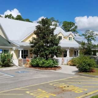 A picturesque building with a light-colored roof surrounded by greenery and a clear sky.