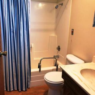 A small bathroom with a blue shower curtain, toilet, sink, and bathtub.