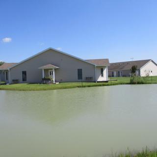 A house by a pond under a clear blue sky.