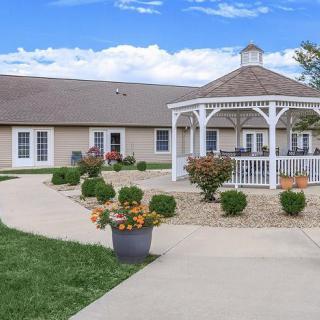 A peaceful garden setting featuring a white gazebo surrounded by well-kept plants and a winding pathway.