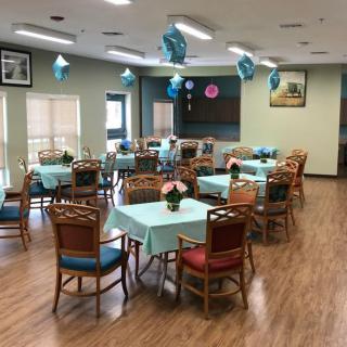 A well-decorated dining area with tables covered in blue tablecloths and balloons hanging from the ceiling.