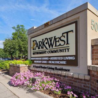Entrance sign for Park West Retirement Community surrounded by flowers and greenery.