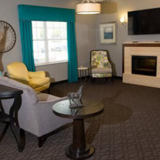 A cozy living room with a sofa, chairs, a fireplace, and a television.