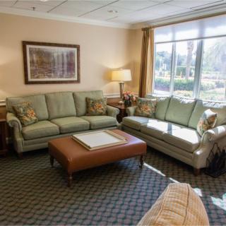 A cozy living room with comfortable sofas, a coffee table, and large windows letting in natural light.