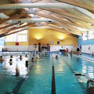 An indoor swimming pool with people engaging in various aquatic activities.