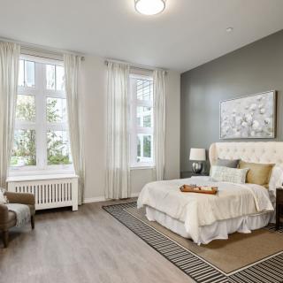 A modern bedroom with neutral colors, featuring large windows and elegant decor.