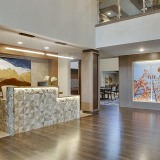 A modern lobby with a stylish reception desk, artwork, and wood flooring.