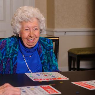 An elderly woman enjoying a game of bingo indoors.