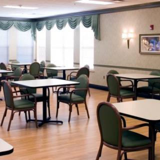 An empty dining room with neatly arranged tables and chairs, featuring large windows and decorative curtains.