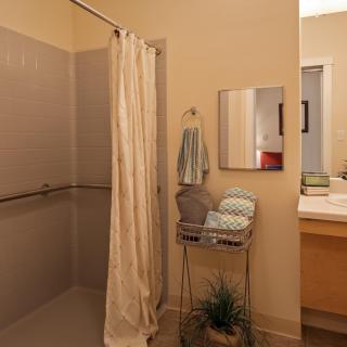A bathroom featuring a shower with a curtain, towels on a rack, and a sink with a mirror.