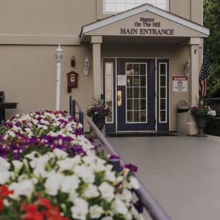 A welcoming entrance adorned with colorful flowers leading to a building's main doorway.