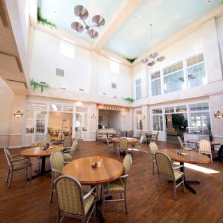 A spacious dining area with multiple tables and chairs, illuminated by a large skylight.