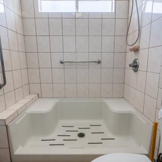 A tiled bathroom with a bathtub and shower setup.