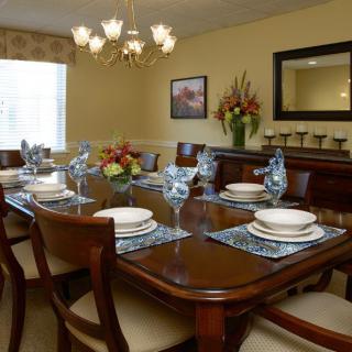 Elegantly set dining room with a large wooden table and chandelier.