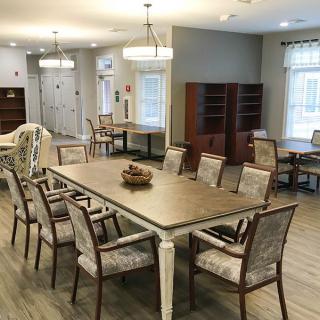 A spacious dining area with a large table and multiple chairs, featuring modern lighting and wooden flooring.