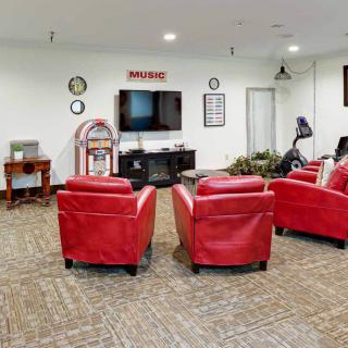 A cozy living room with red chairs facing a television and a classic jukebox.