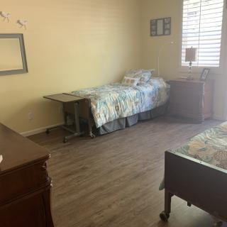 A simple bedroom with a single bed, wooden flooring, and minimal furniture.