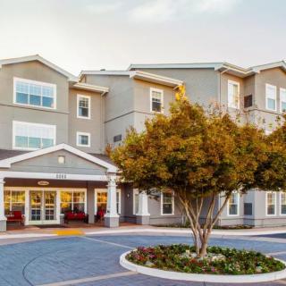 A well-maintained residential building with a tree and landscaped entrance.