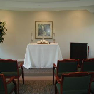 A small chapel setup with an altar and rows of chairs arranged for a ceremony.