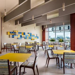 A modern cafeteria interior with yellow tables and colorful artwork on the wall.