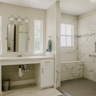 A modern bathroom with a marble-accented shower and a vanity area.