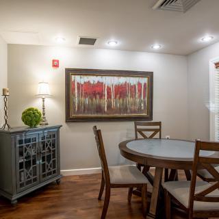 Cozy dining room with a round table, surrounded by wooden chairs and adorned with artwork on the wall.
