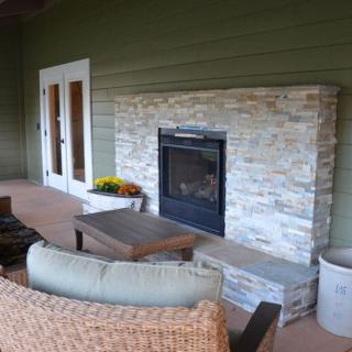 A cozy outdoor patio with a stone fireplace and comfortable seating.