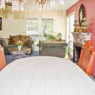 A cozy living room with a dining area, featuring a sofa set, chandelier, and a fireplace.