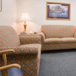 A cozy waiting room with patterned couches, a lamp, and a painting on the wall.