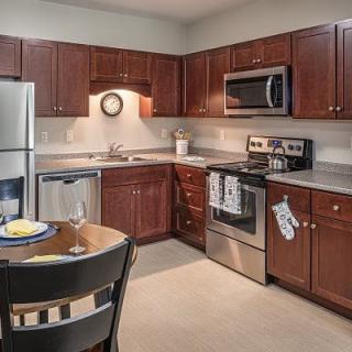 A modern kitchen with stainless steel appliances and wooden cabinetry.