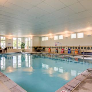 An indoor swimming pool with tiled floors and chairs along the side.