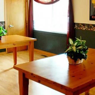 A bright room with wooden tables and potted plants near a window.